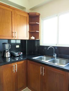 uma cozinha com armários de madeira, um lavatório e uma janela em Espacioso apartamento en Puerto Plata em San Felipe de Puerto Plata