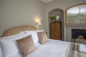 バースにあるArtisan Cottage - Bathのベッドルーム1室(白い枕と暖炉付きのベッド1台付)