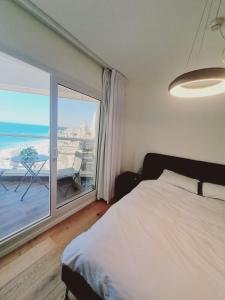 a bedroom with a bed and a large window at תמר על הים in Bat Yam