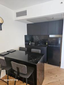 uma cozinha com armários pretos, uma mesa preta e cadeiras em תמר על הים em Bat Yam