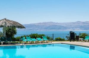 einen Pool mit Stühlen und Meerblick in der Unterkunft Zehava's Zimmer in Ein Gedi