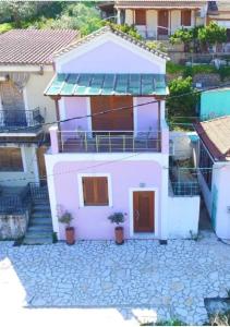 a white house with two potted plants in front of it at Odysseos St. Loft in Vathi