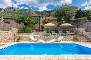 a pool with chairs and umbrellas in front of a house at Villa Cocoon - Vacation Home with Heated Pool & Garden in Bribir