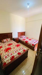 una camera con due letti con fiori rossi di جراند هيلز الساحل الشمالي Grand Hills North Coast شالية فندقي H047 عائلات فقط a Dawwār ‘Abd Allāh Altre 23 foto