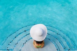Una mujer con sombrero en una piscina en The Oasis at Grace Bay, en Grace Bay