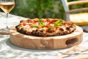 a pizza on a wooden cutting board with a glass of wine at The Oasis at Grace Bay in Grace Bay