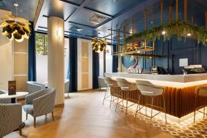 un restaurante con un bar con mesas y sillas en Riu Plaza London Victoria, en Londres