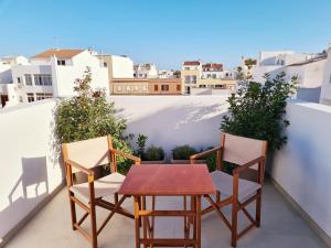 a table and chairs on a balcony with buildings at Waki Conscious Hotel in Ciutadella