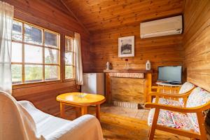 Cabaña de madera con sala de estar con TV y chimenea en Cortijo Huerta Dorotea, en Prado del Rey