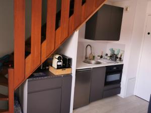 una pequeña cocina con fregadero y una escalera en Appartement Côte Fleurie - MERVILLE FRANCEVILLE PLAGE, en Merville-Franceville-Plage