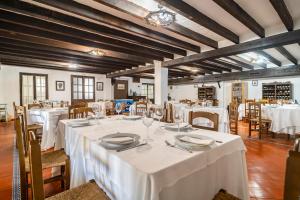 un comedor con mesas y sillas blancas en Cortijo Huerta Dorotea, en Prado del Rey