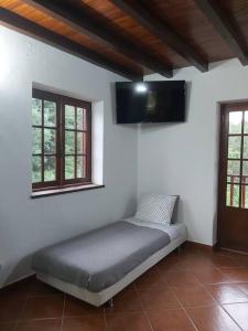 a bed sitting in a room with two windows at Casa Vale Nicolau in Arganil