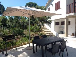 a table and chairs with an umbrella and a grill at Casa Vale Nicolau in Arganil