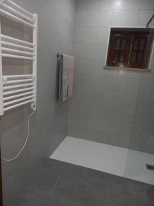 a white bathroom with a shower and a window at Casa Vale Nicolau in Arganil