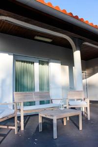 2 bancs en bois et une table sur un patio dans l'établissement Okira beach house, à Aguda