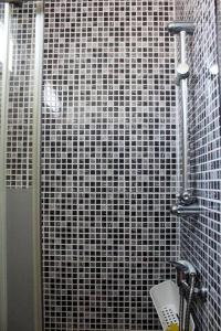 a shower with a black and white tiled wall at Okira beach house in Aguda