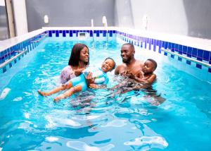 una familia jugando en una piscina en Rushmore - Premier 2 Room, en Lagos