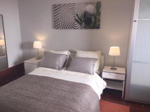 a bedroom with a large bed with two lamps at Casa de Ferias Arrifes in Cascais