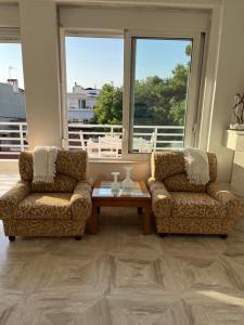 - deux chaises et une table dans le salon avec fenêtres dans l'établissement la PADINI CASA sul mare, à Néoi Epivátai