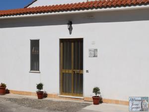 a white building with a brown door and two plants at casa vacanze nonnogennaro in Matonti