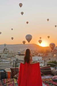 a woman in a red dress looking at hot air balloons at Angel View Suites in Goreme