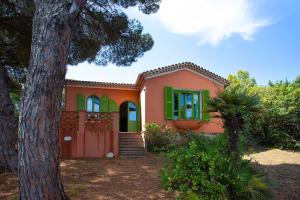 uma casa rosa com janelas verdes e uma árvore em Villa les Grillons em Hyères