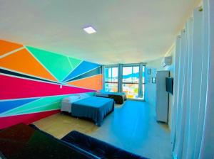 Zimmer mit einer farbenfrohen Wand und 2 Betten in der Unterkunft LOFT ORLA PRAIA GRANDE até 5 pessoas in Arraial do Cabo