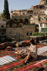 a woman sitting on the floor with a table on a rug at Angel View Suites in Goreme