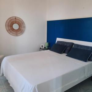 a bedroom with a large white bed with a blue headboard at "CASA SUNSET" in Ischia