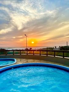 zwei Swimmingpools am Strand bei Sonnenuntergang in der Unterkunft LOFT ORLA PRAIA GRANDE até 5 pessoas in Arraial do Cabo