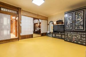 a room with a yellow floor and a tv at Dongmyo Hanok Sihwadang - Private Korean Style House in the City Center with a Beautiful Garden in Seoul