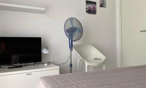 a room with a fan and a tv and a bed at Appartamenti Nataly in Nago-Torbole