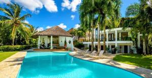 a swimming pool in front of a house with palm trees at Sunny Vacation Villa No 75 in San Rafael del Yuma