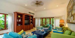 sala de estar con sofás azules y TV en Sunny Vacation Villa No 75, en San Rafael del Yuma