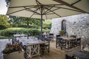 eine Terrasse mit Tischen, Stühlen und einem Sonnenschirm in der Unterkunft Agriturismo La Casa Di Rodo in Quarrata