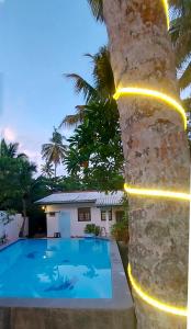 a villa with a swimming pool next to a palm tree at Calm Villa Wadduwa in Wadduwa