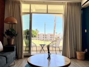 a living room with a coffee table in front of a large window at SM Apartments in San José del Cabo