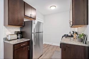 eine Küche mit einem Kühlschrank aus Edelstahl und Holzschränken in der Unterkunft Chic & Fully Furnished Studio Apt with Laundry - Brompton 61-66 rep in Chicago