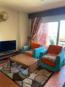 a living room with two chairs and a tv at Gulf Porto Marina Call First in El Alamein