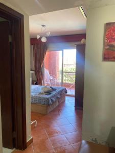 1 dormitorio con 1 cama y puerta a un balcón en Gulf Porto Marina Call First, en El Alamein