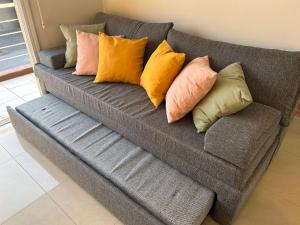 eine graue Couch mit verschiedenen farbigen Kissen darauf in der Unterkunft DEPARTAMENTO DEL PASEO in Bahía Blanca