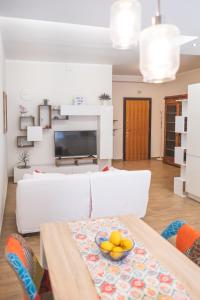 a living room with a white couch with a bowl of fruit on a table at Cozy flat with terrace at Trastevere train station in Rome