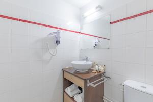 a white bathroom with a sink and a mirror at Appart'City Confort Pau Centre in Pau