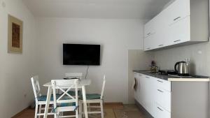 a kitchen with white cabinets and a table and chairs at B&B Hills Bihać in Bihać
