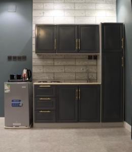 a kitchen with black cabinets and a sink and a refrigerator at شقق فاتوران الفاخره in Al Madinah