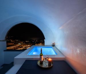 uma piscina com uma garrafa de vinho e copos em Pyrgos Cave Suites em Pírgos