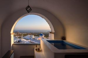 an arch shaped bathtub in a room with a window at Pyrgos Cave Suites in Pirgos