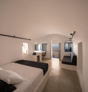 a white bedroom with a bed and a desk at Pyrgos Cave Suites in Pirgos