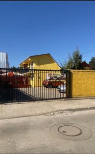 una cerca negra con un edificio amarillo y una calle en Cabañas Dichato Turismo Roma, en Dichato