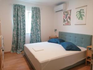sypialnia z łóżkiem z niebieskimi poduszkami i oknem w obiekcie Apartmani Mares - 20 m from the beach w Breli
